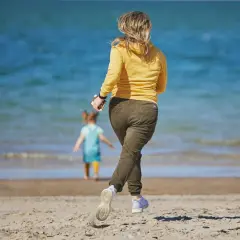 Kobieta biegnie do dziecka w wodzie. Sen o tym, jak ratować kogoś z wody, może oznaczać potrzebę ochrony bliskich.