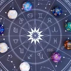 Kości do gry z symbolami zodiaku i cyframi, w tym kostka z numerologiczną 10, leżą na tle wykresu astrologicznego.