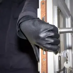 Ręka w czarnej rękawiczce otwiera drzwi, klucze wiszą na zamku. Sen o włamanie może oznaczać niepokój.