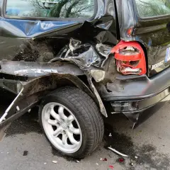 Czarny samochód po wypadku, z pogiętym tyłem i rozbitym światłem. Jakby z sennika, czarny samochód w takim stanie budzi niepokój.