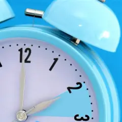 Niebieski budzik z dzwonkami. Wskazówki pokazują 01:01, co symbolizuje znaczenie zmiany czasu.