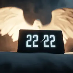 Zegar pokazuje 22:22, a za nim widnieją świetliste skrzydła. To znak, że 22 22 znaczenie dla singli może oznaczać nowy początek.
