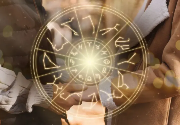 Zodiakalny krąg z symbolami gwiazd, w tym maj, otacza dłonie pary.