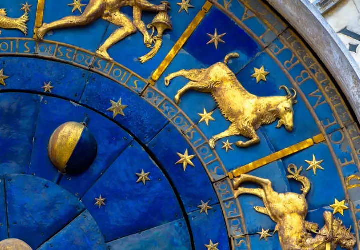 Złote figury Koziorożca i innych znaków zodiaku na niebieskiej tarczy zegara. 19 stycznia to czas Koziorożca.