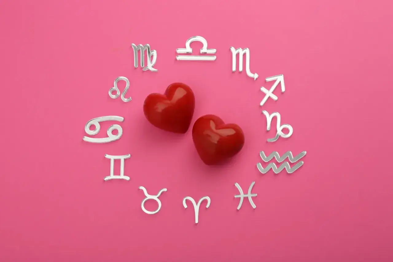 Dwa czerwone serca otoczone srebrnymi symbolami zodiaku. Dziś horoskop na dziś Waga miłosny zapowiada gorące uczucia.