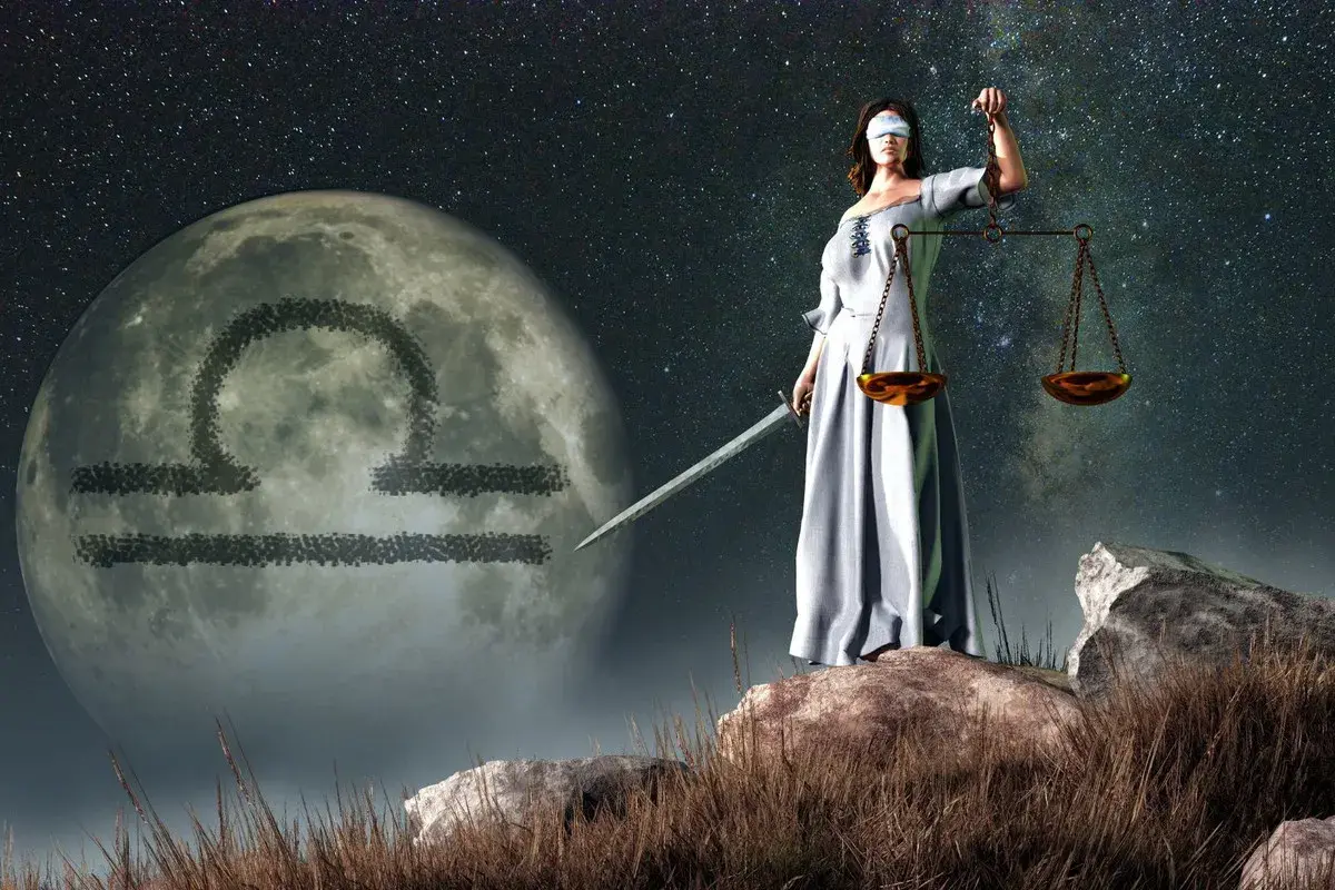 Kobieta z przepaską na oczach, trzymająca wagę i miecz, stoi na tle księżyca z symbolem Wagi. Ascendent w wadze.