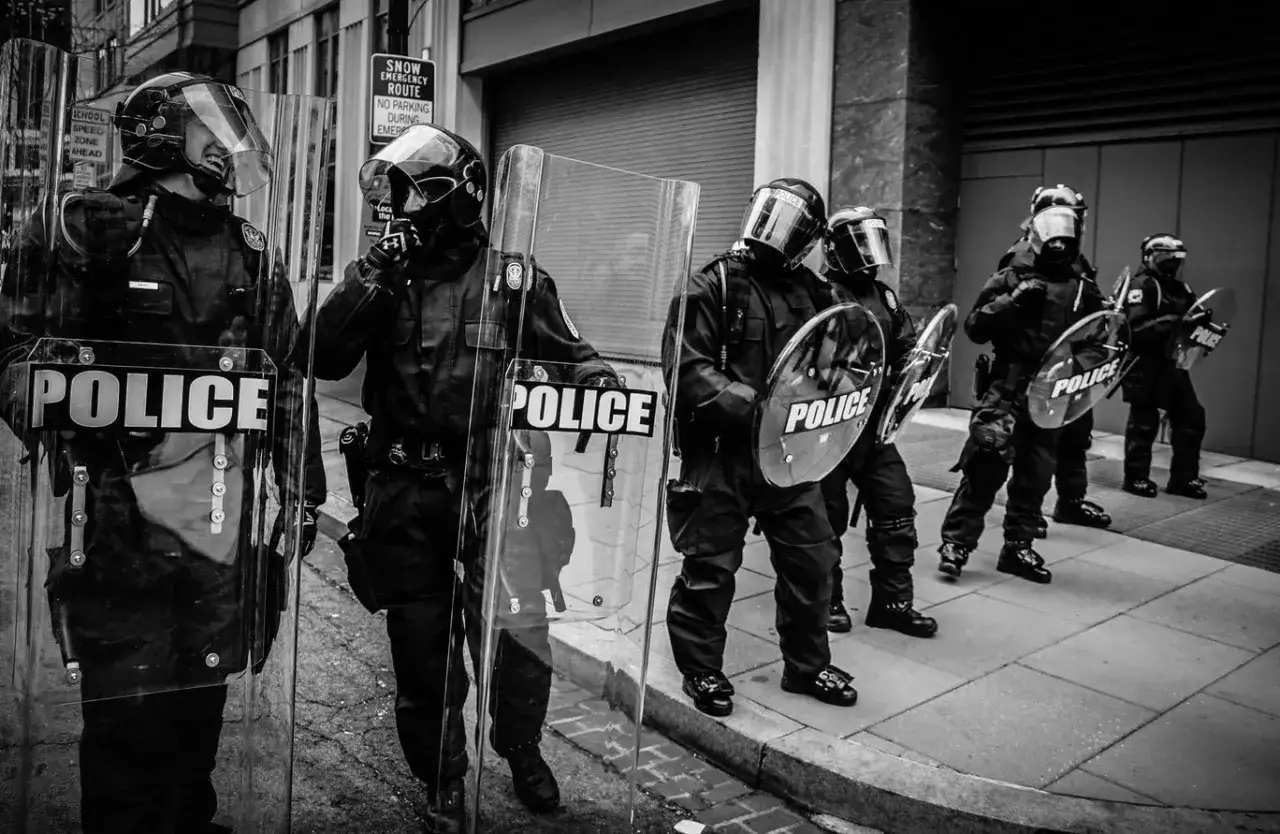 Policjanci w pełnym rynsztunku, z tarczami z napisem 